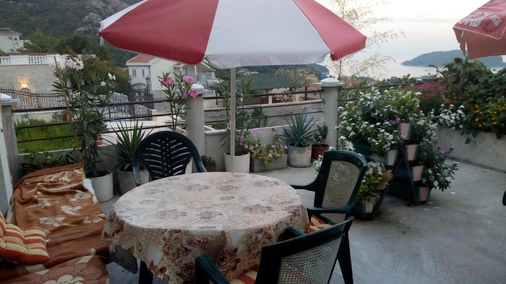 a table and chairs with an umbrella on a balcony at Georgijevic Room & Apartments in Budva