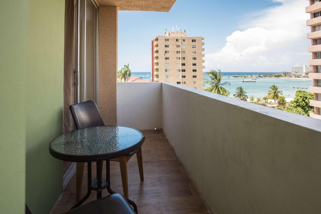 a table and chair on a balcony with a view of the ocean at Emerald One Bedroom Suite At Turtle Towers in Ocho Rios
