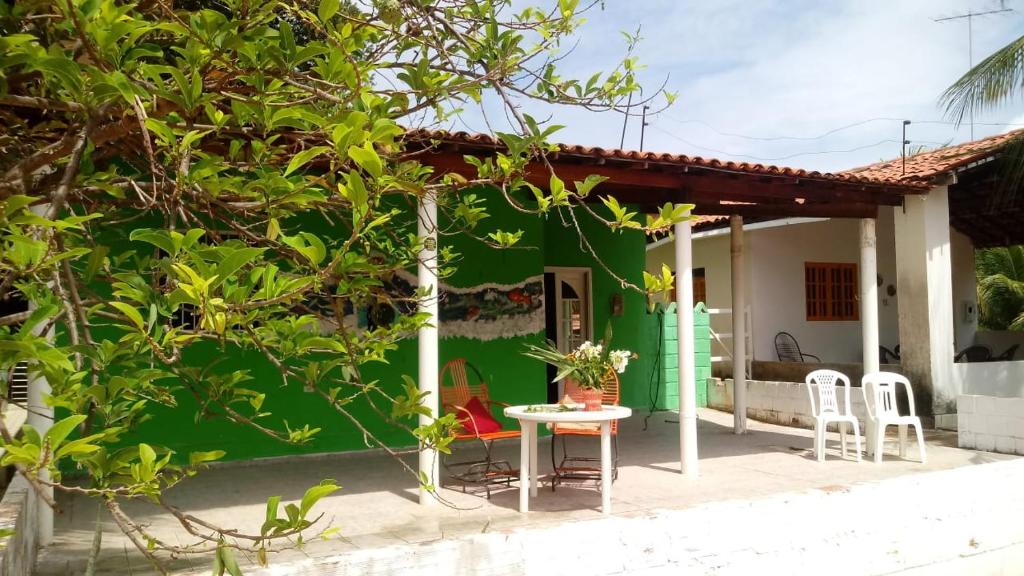 una pequeña casa con una pared verde, una mesa y sillas en Aconchego em Maragogi, en Maragogi