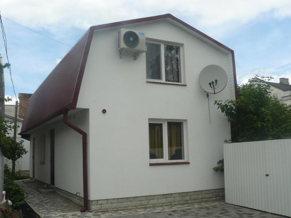 ein weißes Haus mit einem Fenster und einem Ventilator in der Unterkunft Hostynnyi Botsiun in Dubno