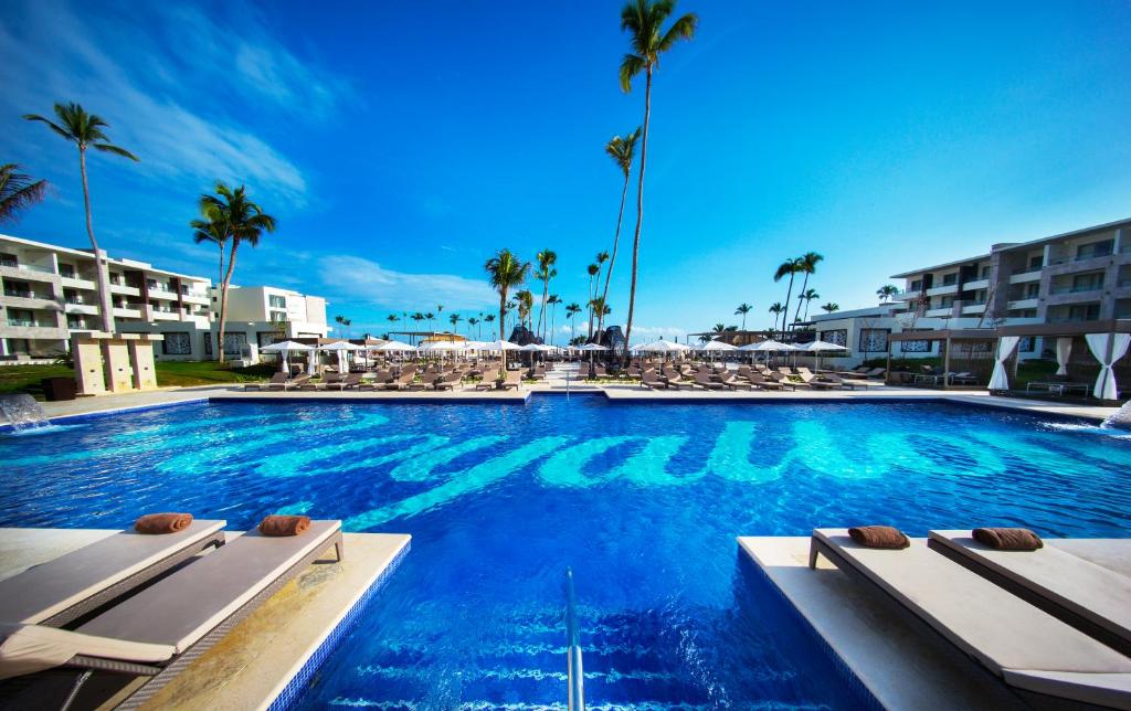 a large swimming pool with chairs and palm trees at Royalton Bavaro, An Autograph Collection All-Inclusive Resort & Casino in Punta Cana