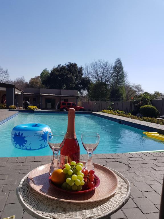 a tray of fruit and wine glasses next to a swimming pool at Rekky Signature Guesthouse in Johannesburg