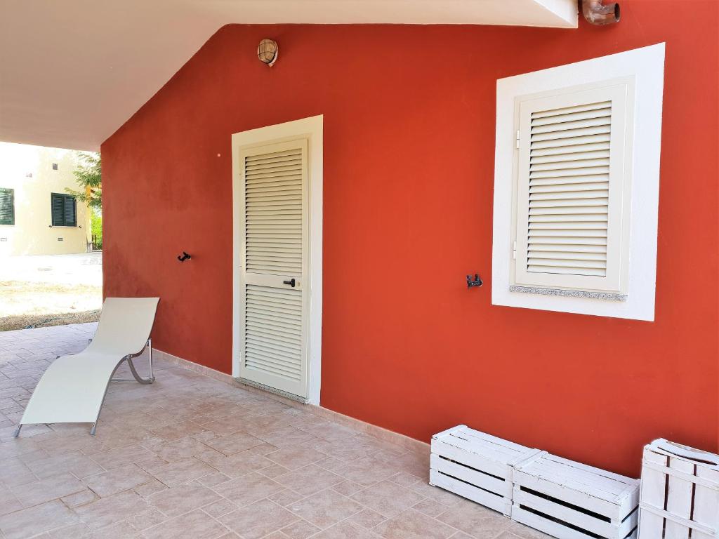 pared roja con 2 ventanas y silla blanca en La Cantoniera, en Campanedda