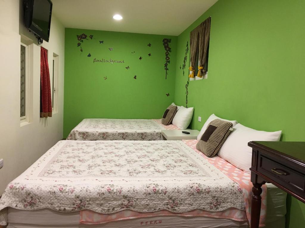 a bedroom with two beds with green walls at Share B&amp;B in Puli