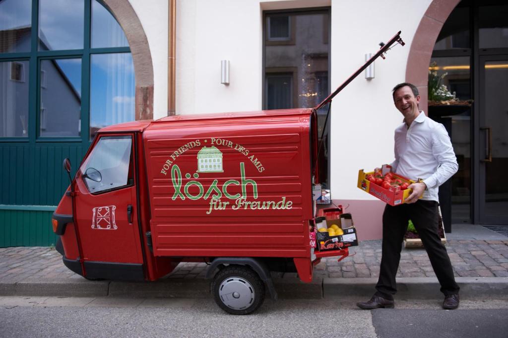 HornbachにあるLösch für Freundeの赤い食料品車の横に立つ男