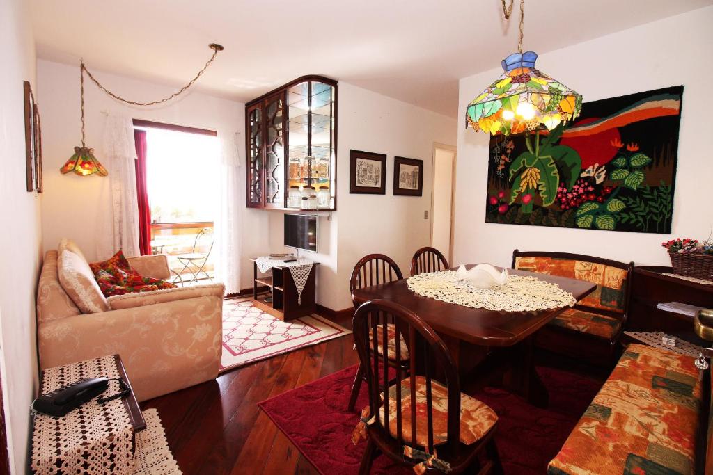 a living room with a table and a couch at Apartamento Vista para as Montanhas in Campos do Jordão