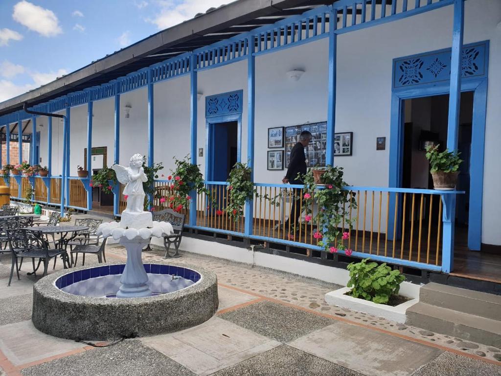 a fountain in front of a building with tables and chairs at Casa Hotel El Compadre in Filandia