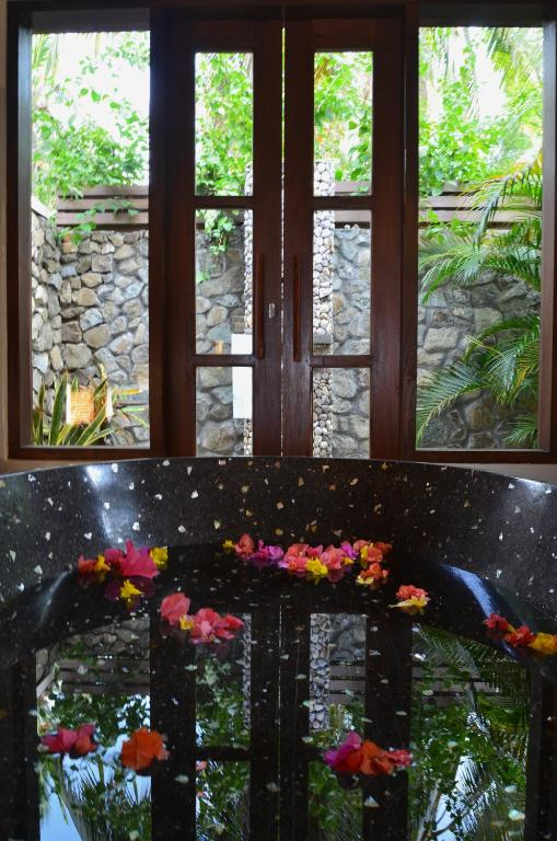 a bench with flowers in front of a window at Cocotinos Sekotong Lombok in Sekotong