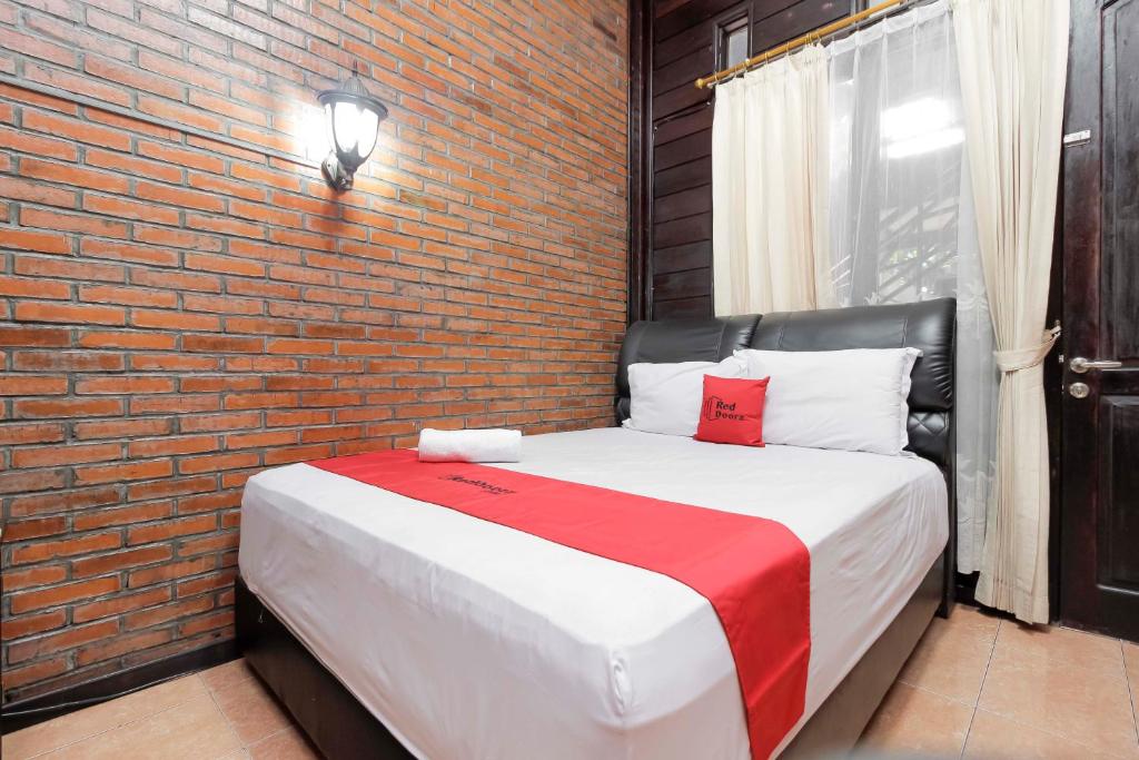 ein Schlafzimmer mit einem großen Bett mit Ziegelwand in der Unterkunft RedDoorz @ Cilandak Timur in Jakarta