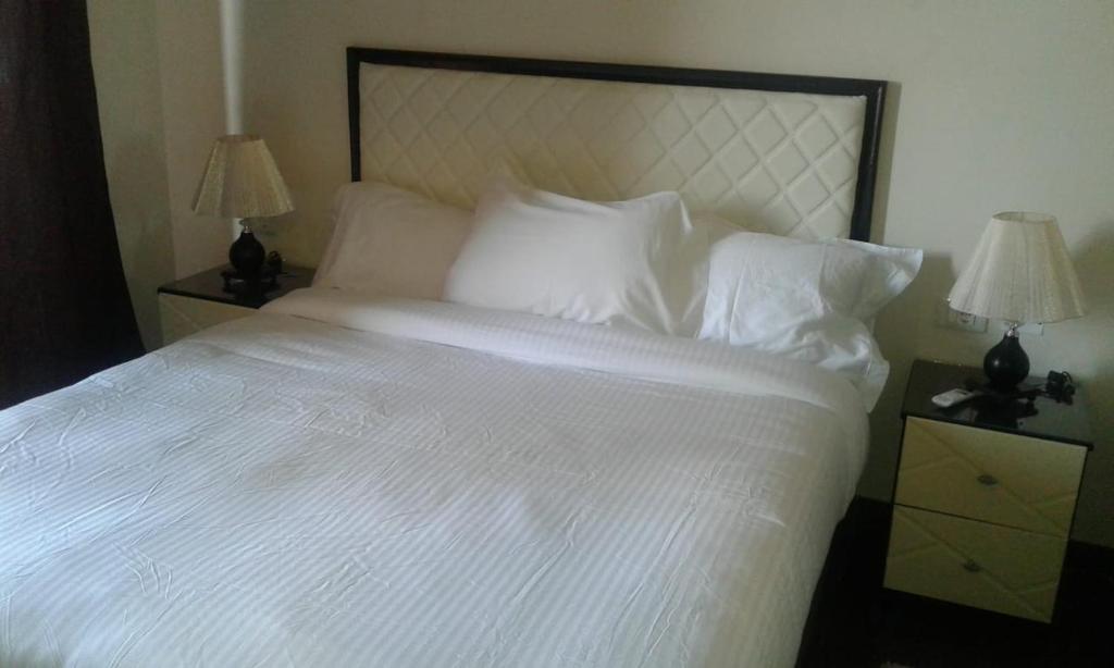Una cama con sábanas blancas y almohadas en un dormitorio en Apartment in Porto Sharm VIP en Sharm El Sheikh
