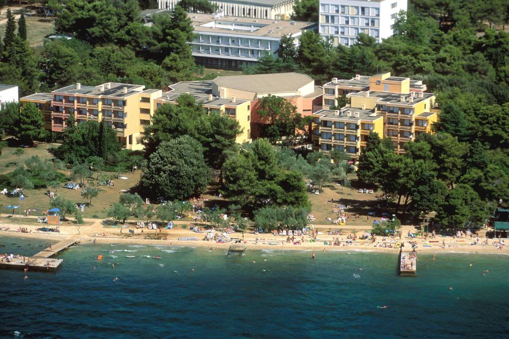 un groupe de personnes sur une plage avec des bâtiments dans l'établissement Hotel Donat - All Inclusive, à Zadar