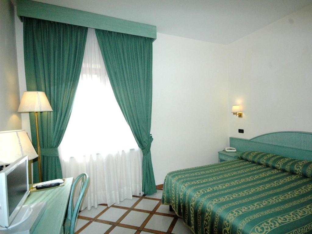 a bedroom with a bed and a window with green curtains at Residence Villaggio Verde in Sorrento