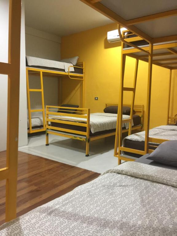 a room with three bunk beds and a yellow wall at Phuket Sunny Hostel in Phuket Town