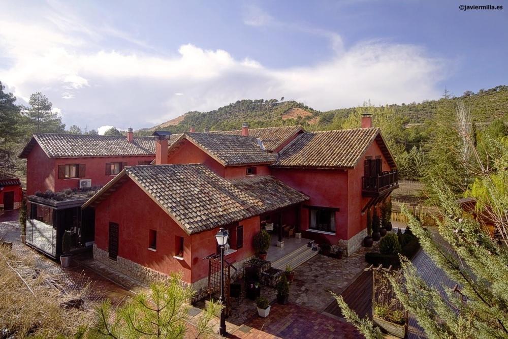 an aerial view of a red house with mountains in the background at La Casita de Cabrejas in Jábaga