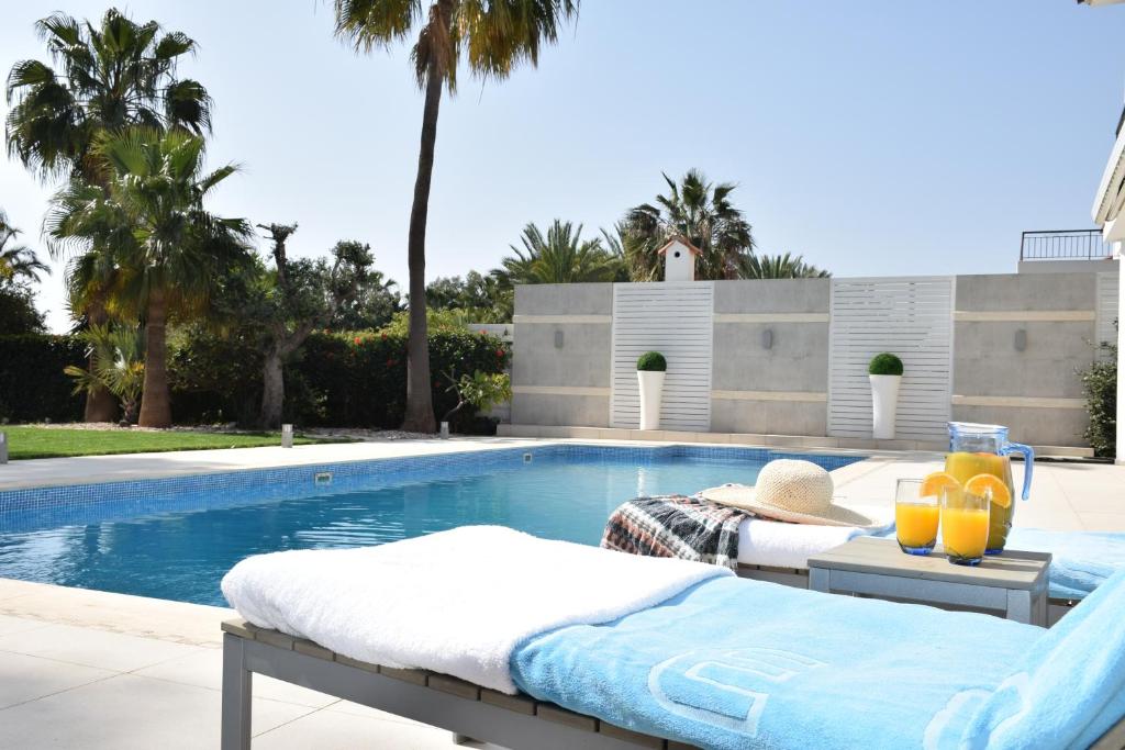 a swimming pool with two beds next to a swimming pool at Deluxe First Line Villa in Pervolia