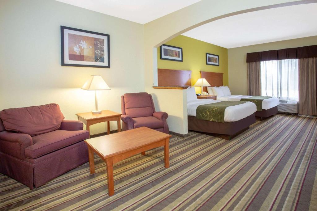 a hotel room with a bed and a couch and chair at Baymont by Wyndham Marion in Marion