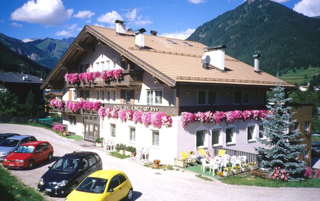 a large building with flowers on the side of it at Hotel Villa Mozart in Pozza di Fassa