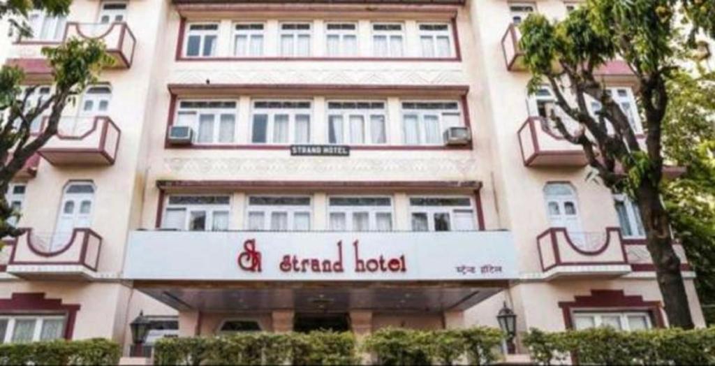 un grande edificio con un cartello sulla parte anteriore di Strand Hotel, Colaba a Mumbai