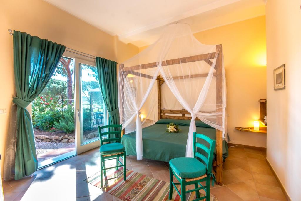 a bedroom with a canopy bed and two chairs at Tenuta Valdelmelo in Castiglione della Pescaia