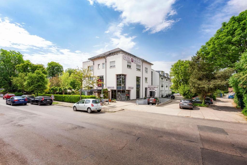 ein weißes Gebäude mit Autos auf der Straße in der Unterkunft Hotel Hiemann - Superior in Leipzig