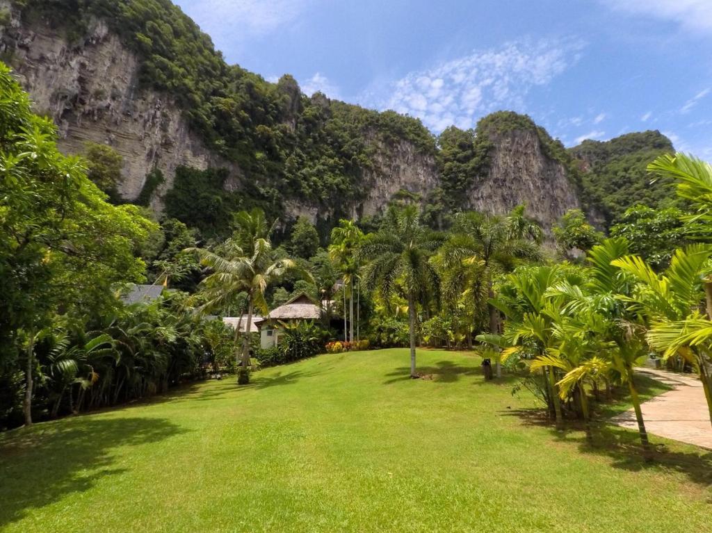 une pelouse avec des palmiers et des montagnes en arrière-plan dans l'établissement Vipa Tropical Resort, à Ao Nang Beach