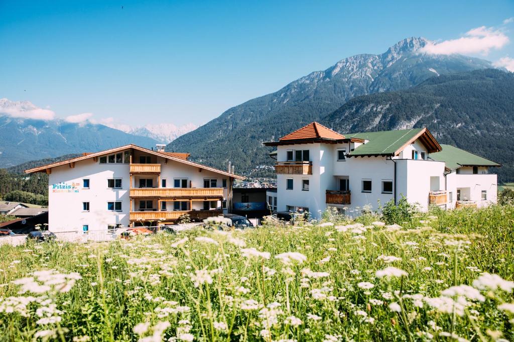 un groupe de bâtiments dans un champ de fleurs dans l'établissement Pitzis Kinderhotel - Family Only, à Arzl im Pitztal