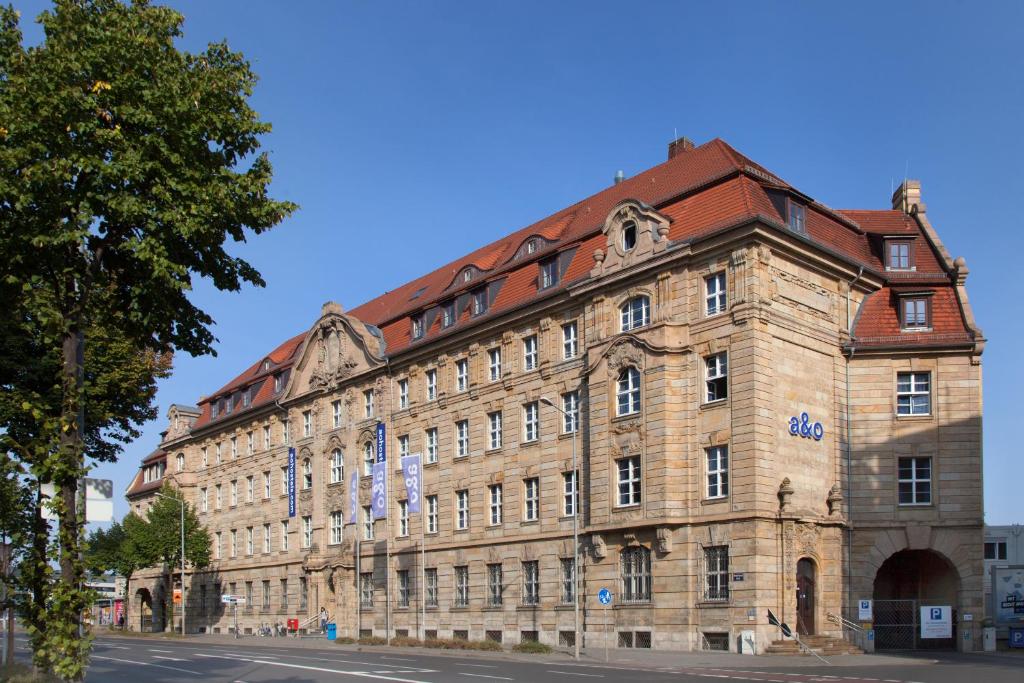 ein großes Steingebäude mit rotem Dach in der Unterkunft a&o Leipzig Hauptbahnhof in Leipzig