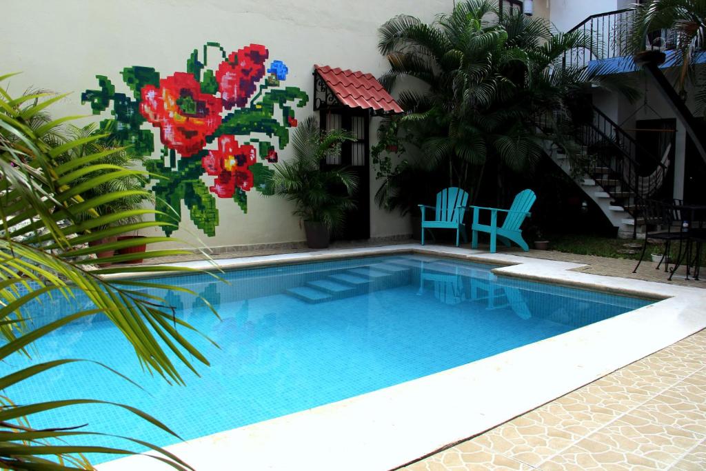 una piscina con 2 sillas azules y flores en Casa Akbal B&B en Mérida