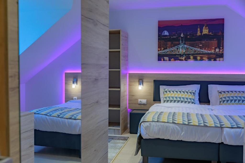 two beds in a room with purple lighting at Christina Residence in Budapest