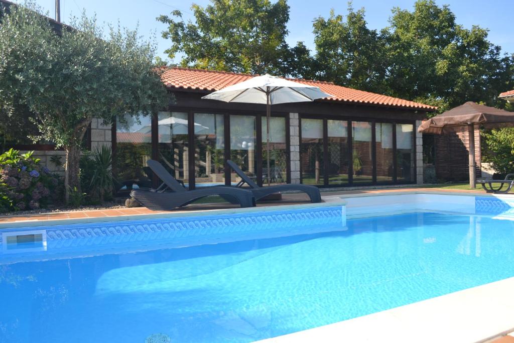 a swimming pool with two chairs and an umbrella at Alagoas4Family - Country House in Arouca