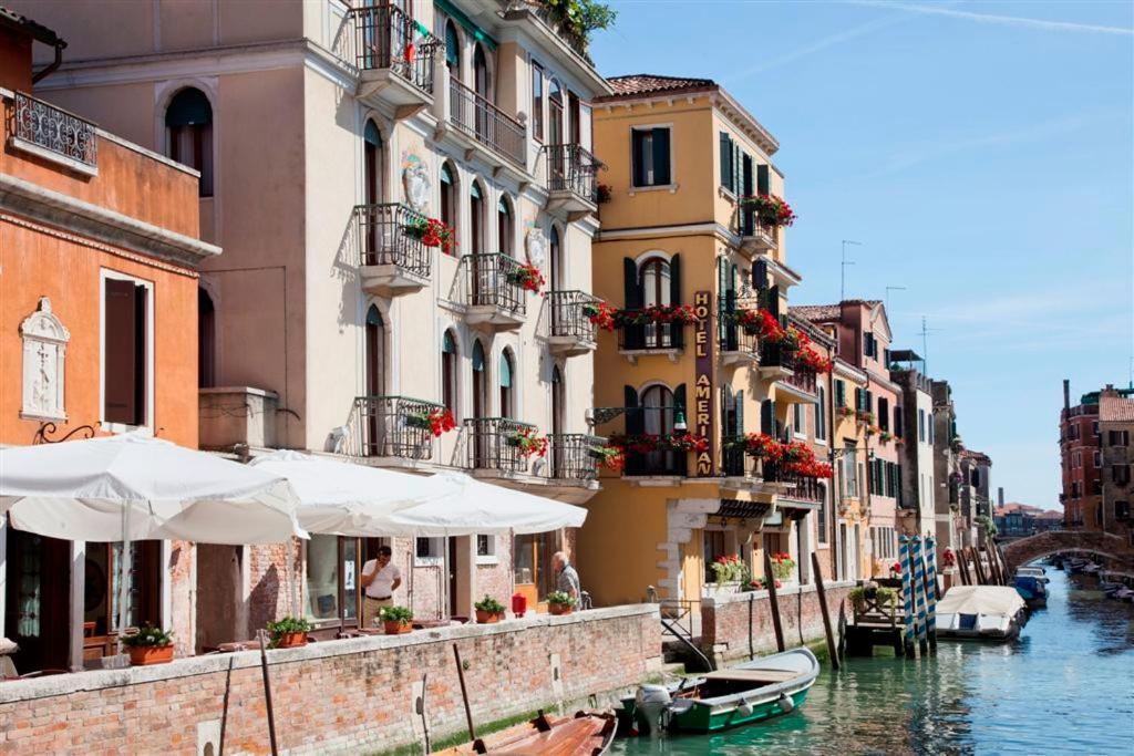 a group of buildings next to a canal with boats at Hotel American-Dinesen in Venice