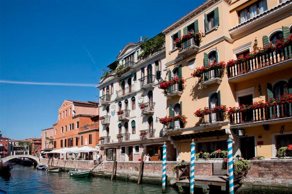 a building next to a canal with a boat in the water at Hotel American-Dinesen in Venice