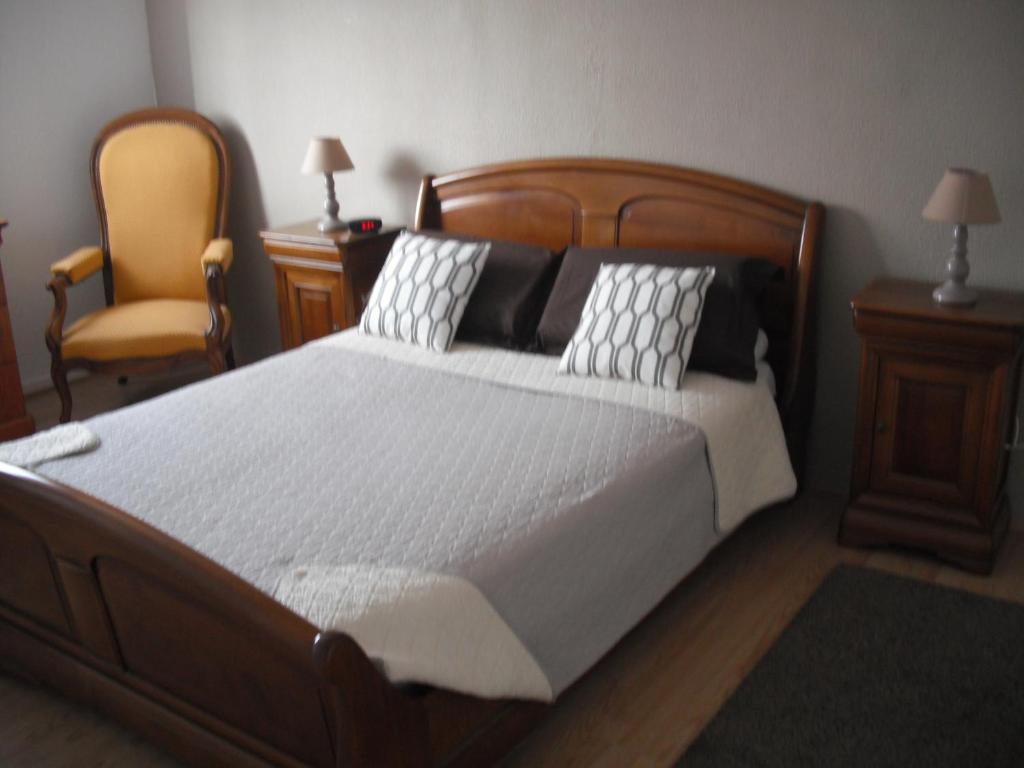 ein Schlafzimmer mit einem großen Bett und einem Stuhl in der Unterkunft Residence Le Vendome in Dijon