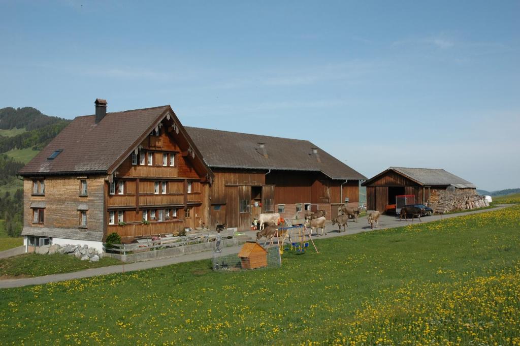 um grande celeiro de madeira com animais à sua frente em Ferienwohnung Brülisauer em Brülisau