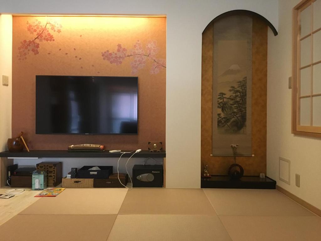 un soggiorno con TV a schermo piatto a parete di Tokyo inn Sakura An a Tokyo