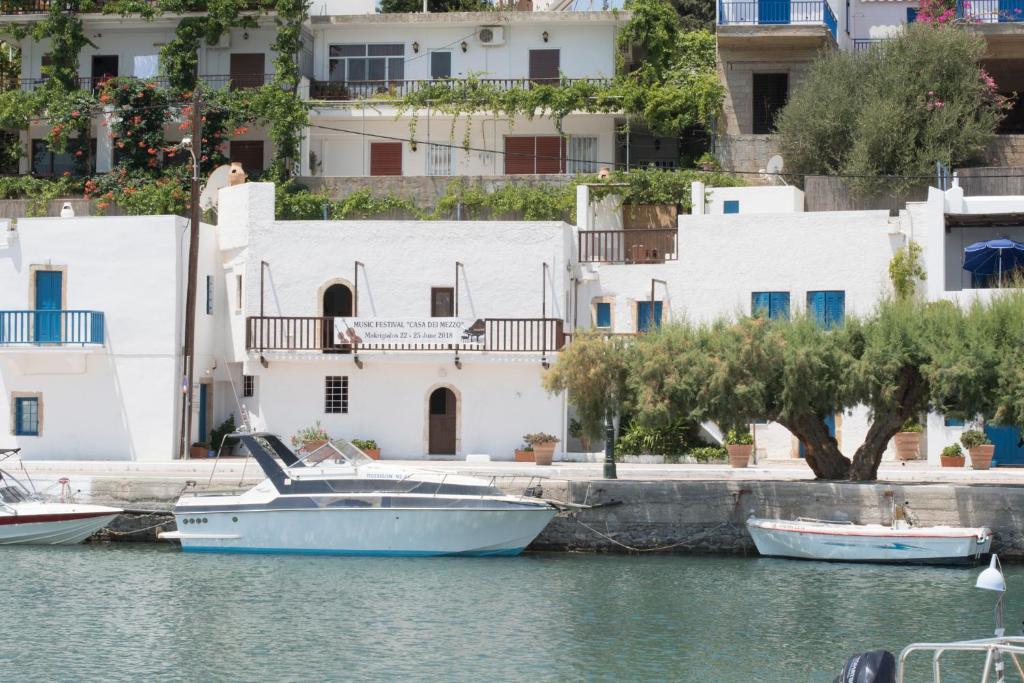 a boat in the water in front of buildings at Τhe White Houses in Makry Gialos