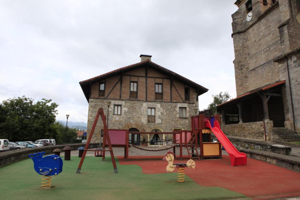 un parque infantil frente a un edificio antiguo con zona de juegos en Albergue Uztartza, en Aduna