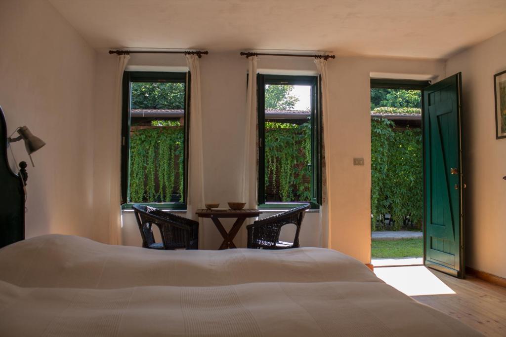 a bedroom with a bed and a table and windows at Il Fojot in La Cassa