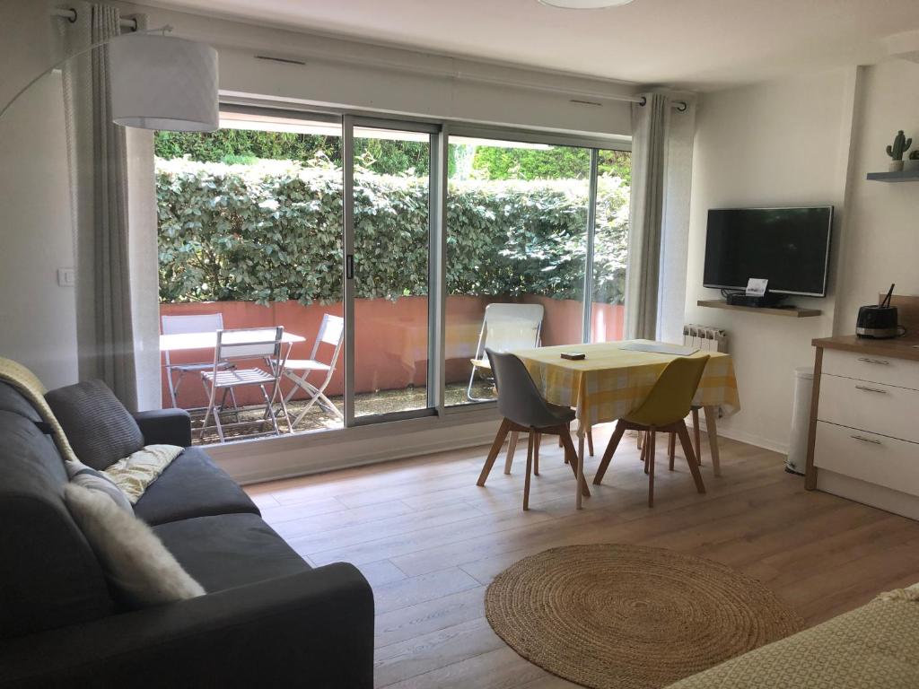 uma sala de estar com um sofá e uma mesa com cadeiras em Beau Studio à la Plage em Anglet