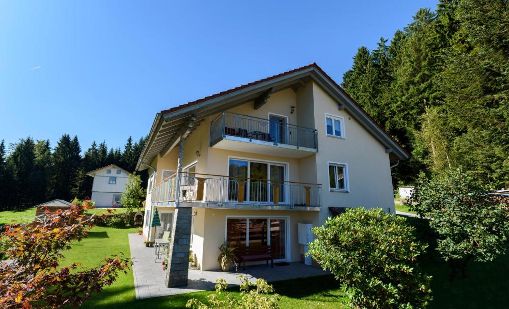 Casa blanca grande con balcón y árboles en Ferienwohnung Holzinger, en Hauzenberg