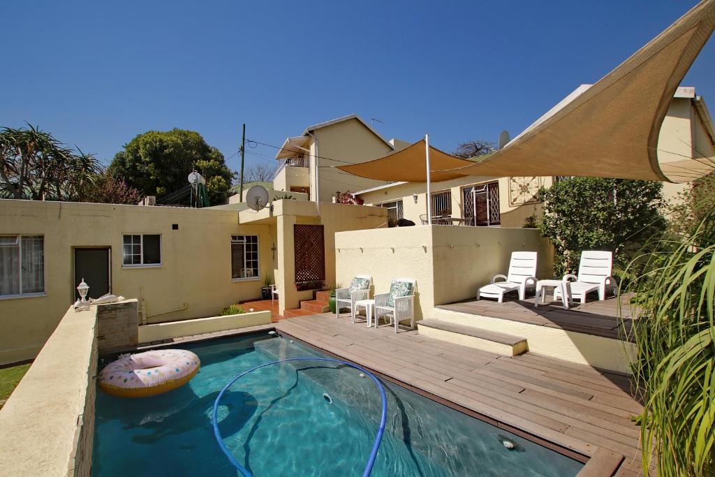 a swimming pool with a wooden deck and a house at Arum Place Guest House in Johannesburg