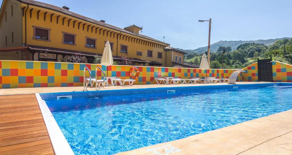 een zwembad met stoelen en parasols naast een gebouw bij Hotel El Angliru in Soto de Cangas