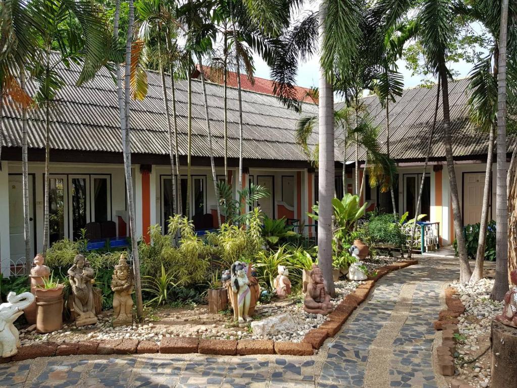 een tuin met beelden voor een gebouw bij Sam's House Kanchanaburi in Kanchanaburi