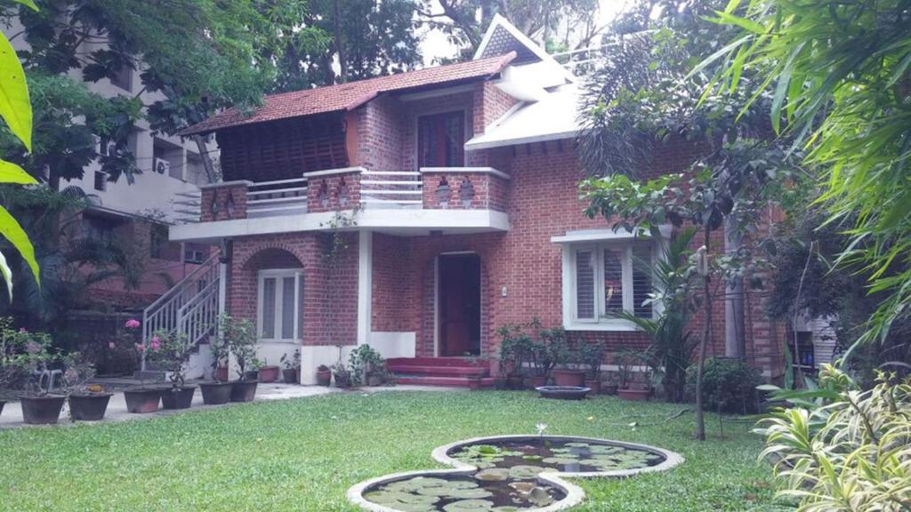 une maison en briques avec un étang dans la cour dans l'établissement Tagore Homestay Villa Trivandrum, à Trivandrum