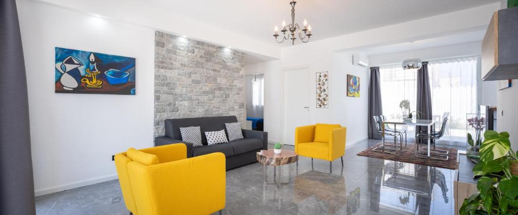 a living room with yellow chairs and a couch at Arricàmpati Apartments Villa & Bringo Car Rental in Carini