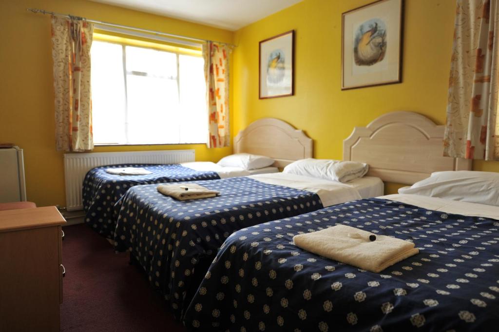 a hotel room with three beds with towels on them at Acton Town Hotel in London