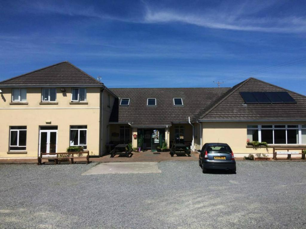 a house with a car parked in a parking lot at The Mourne Lodge "Cnocnafeola" in Kilkeel