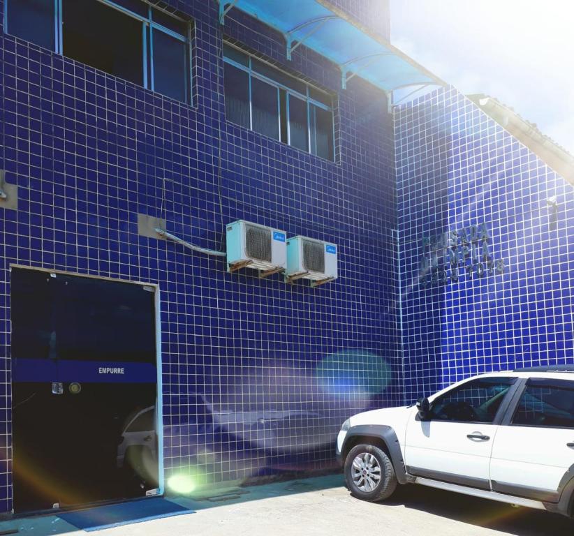 馬塞約的住宿－POUSADA OLÍMPIA，停在蓝色瓷砖建筑前的白色汽车