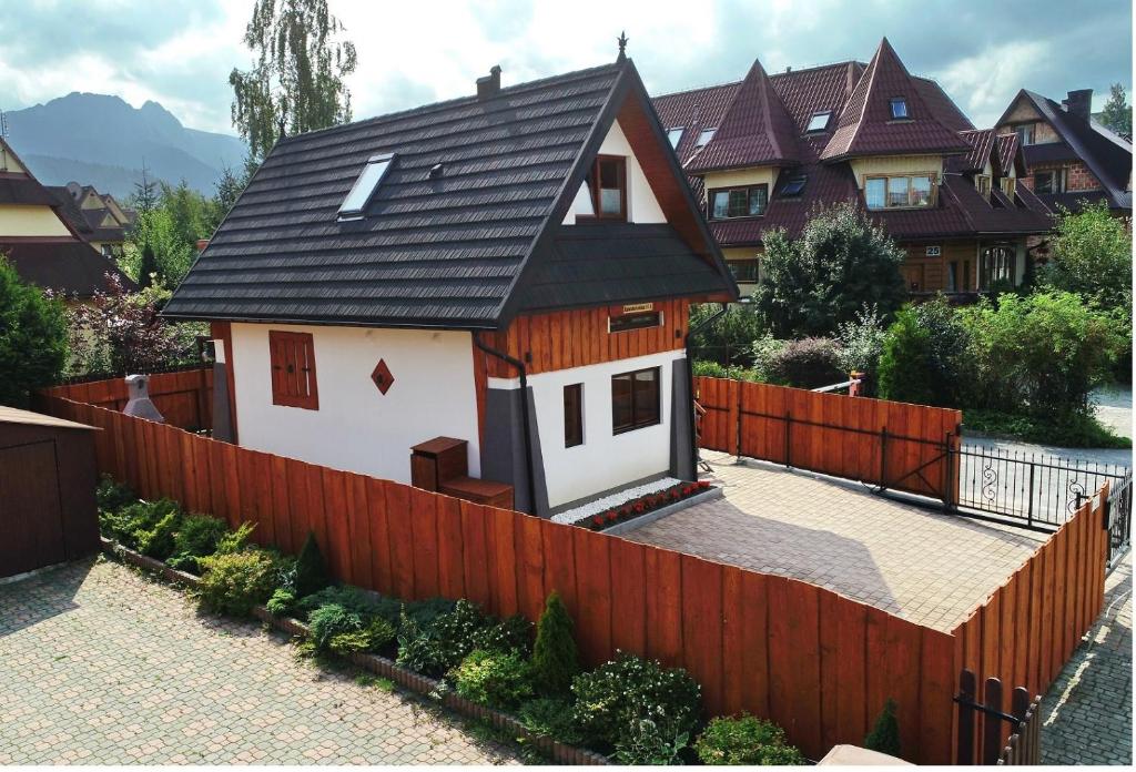 a house with a black roof and a fence at Domek pod Antałówką in Zakopane