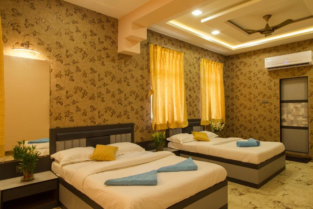 a bedroom with two beds with yellow and blue pillows at Hotel Tourister in Mumbai